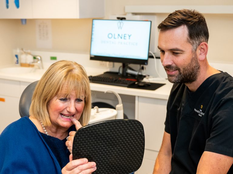 A dentist holding a mirror so that his patient can examine the work he has completed