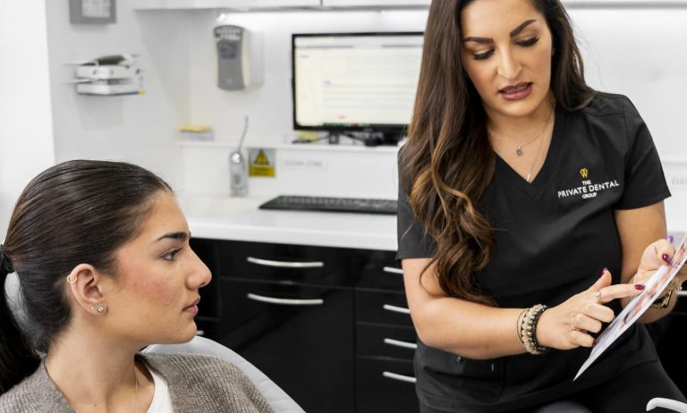 Dentist in black scrubs discussing dental implants with a patient