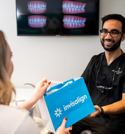 Dentist handing Invisalign product to patient in dental surgery